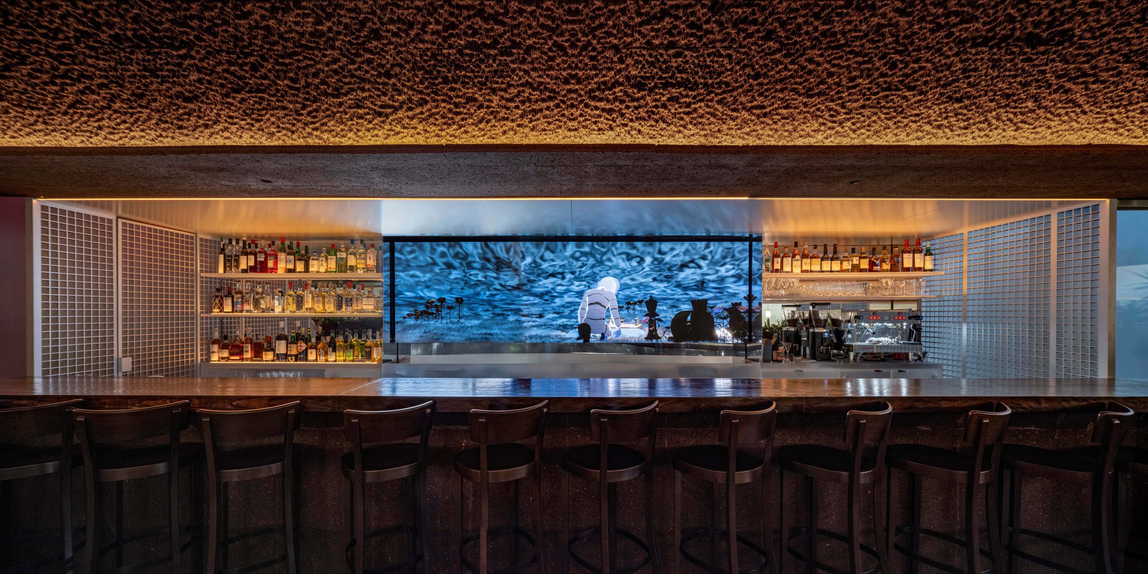 An interactive digital artwork by Ian Cheng displayed behind a bar