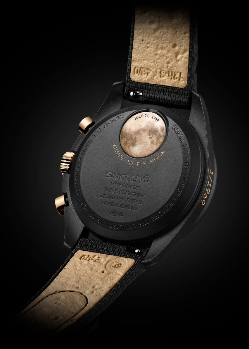 Photo of the reverse of the gold MoonSwatch showing a gold moon battery cover on the black case and a golden brown strap lining with a pockmarked texture similar to the surface of the moon