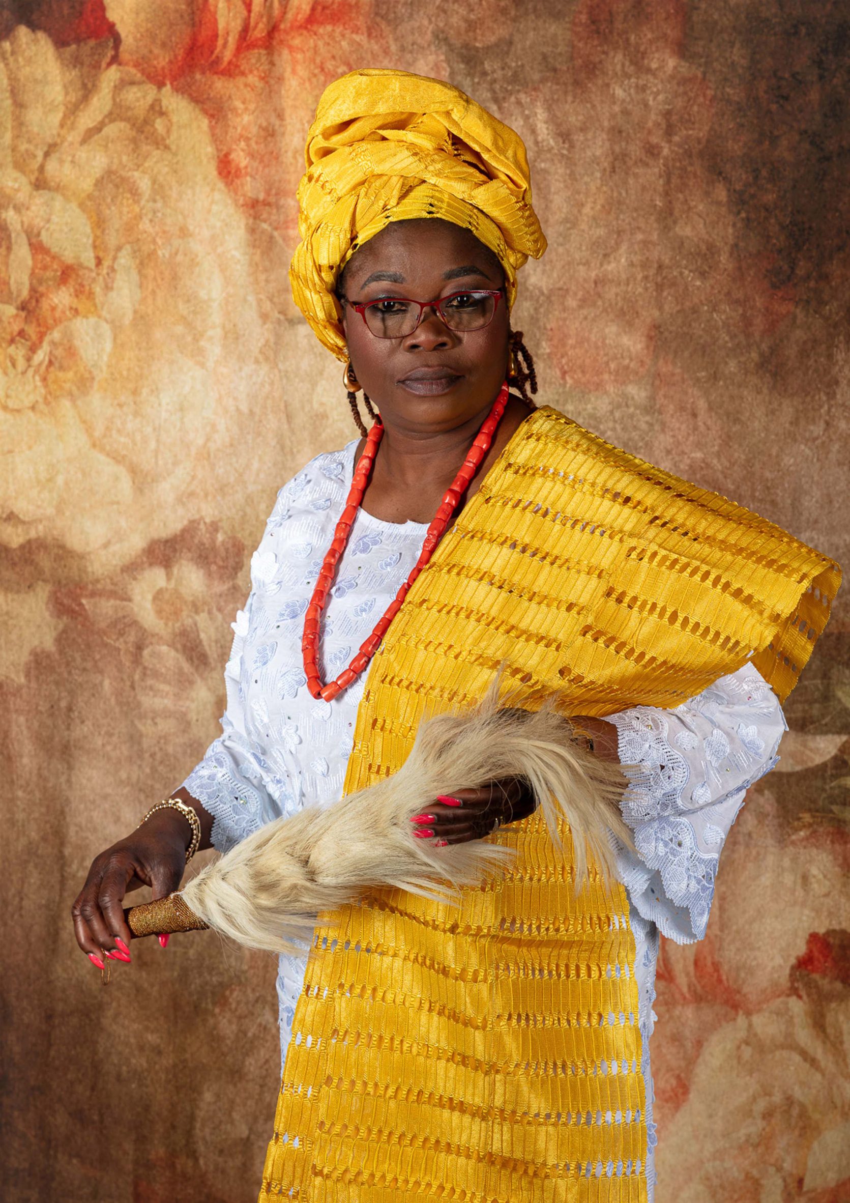 Model wearing bright yellow garment and headpiece and bright orange necklace