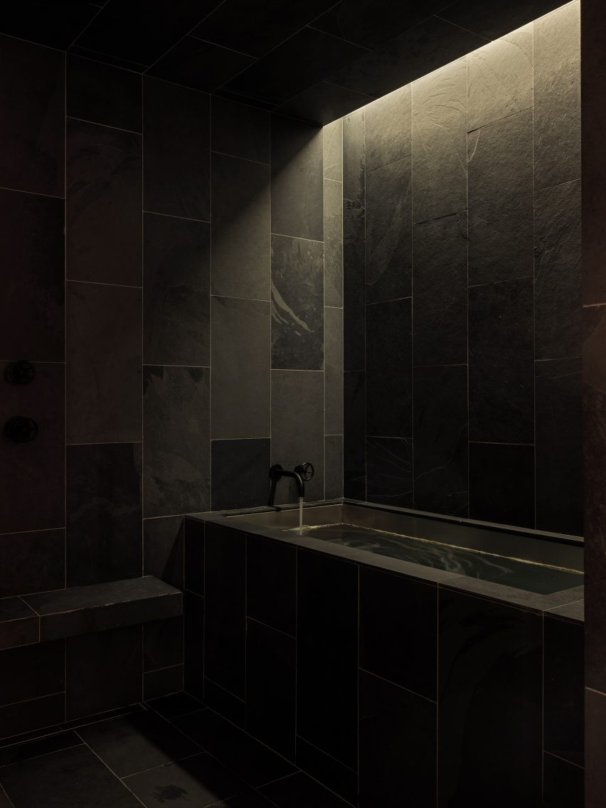 A single shaft of light above a bath highlights the texture of slate
