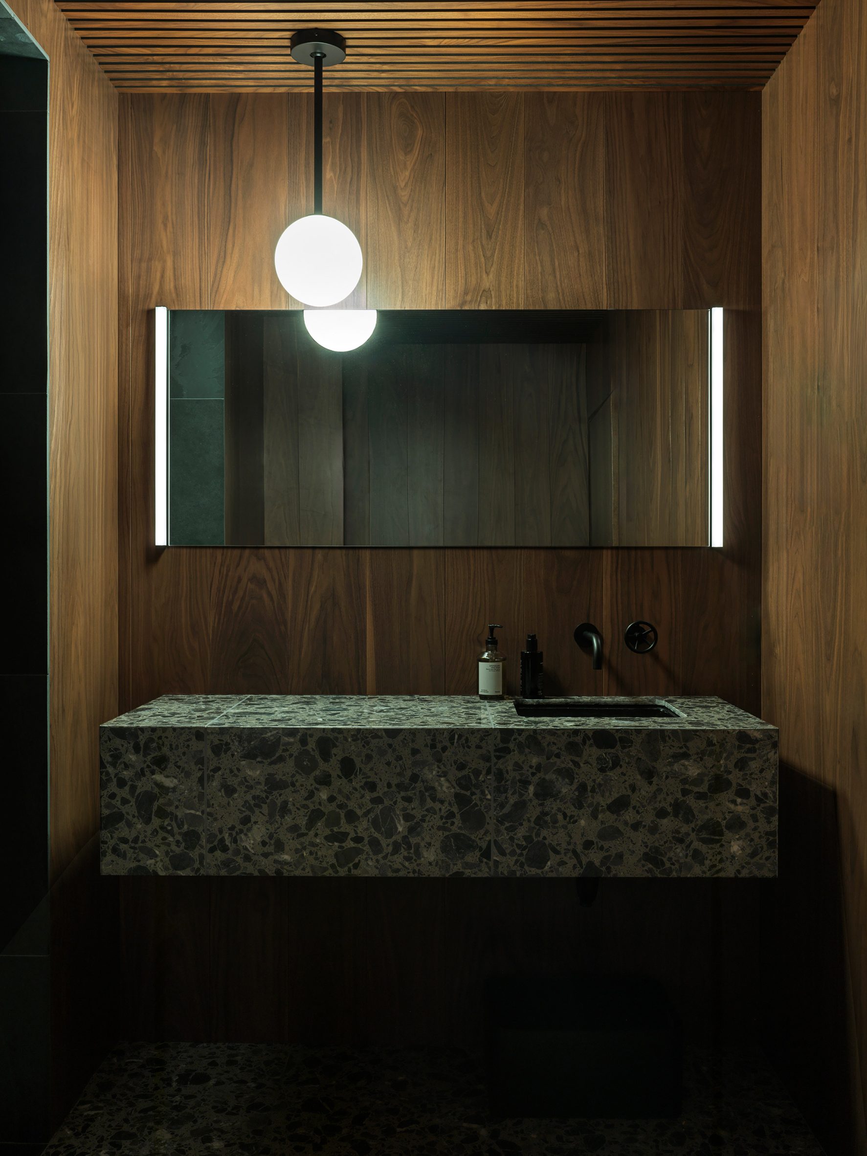 Walnut-lined changing area with a terrazzo vanity