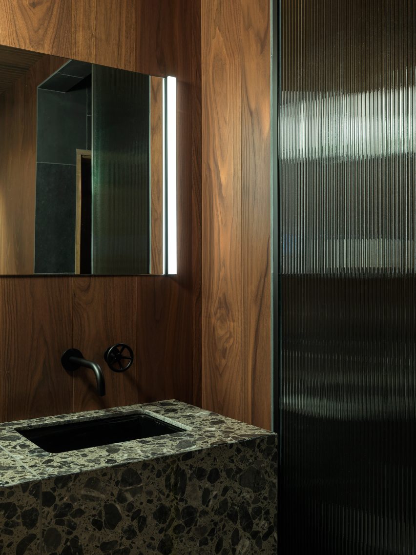 A terrazzo vanity and fritted glass partition within a changing room