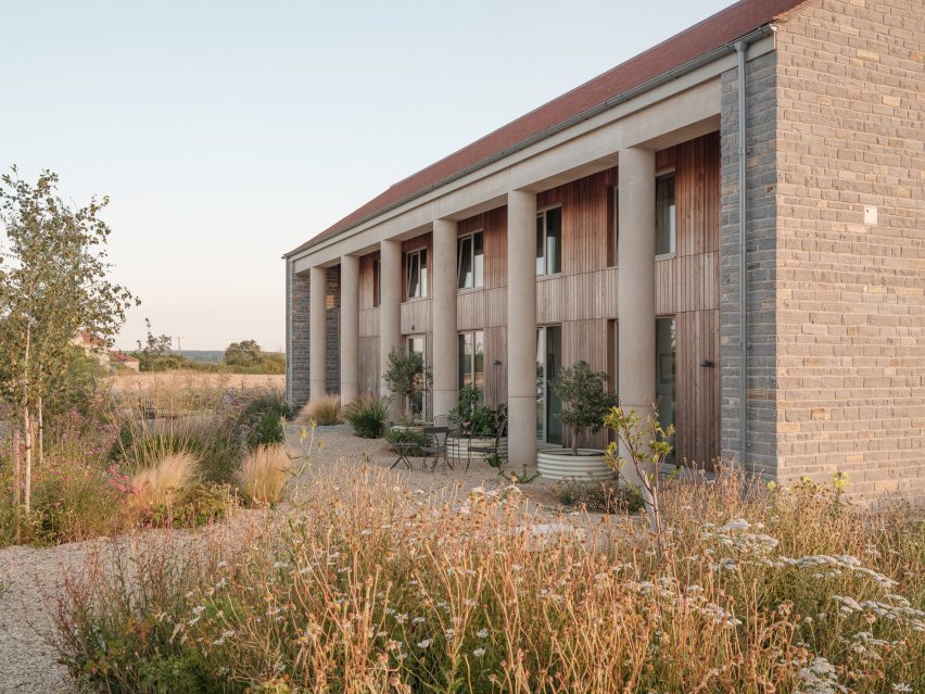 Oblique view along the length of the house showing the row of cylindrical concrete columns and landscaped garden