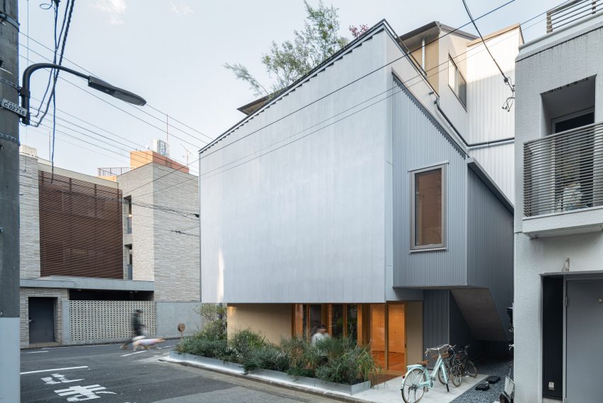 Rear view of Tokyo Ballet House showing planted borders, the ribbed facade and the upper residential volume set back above the street