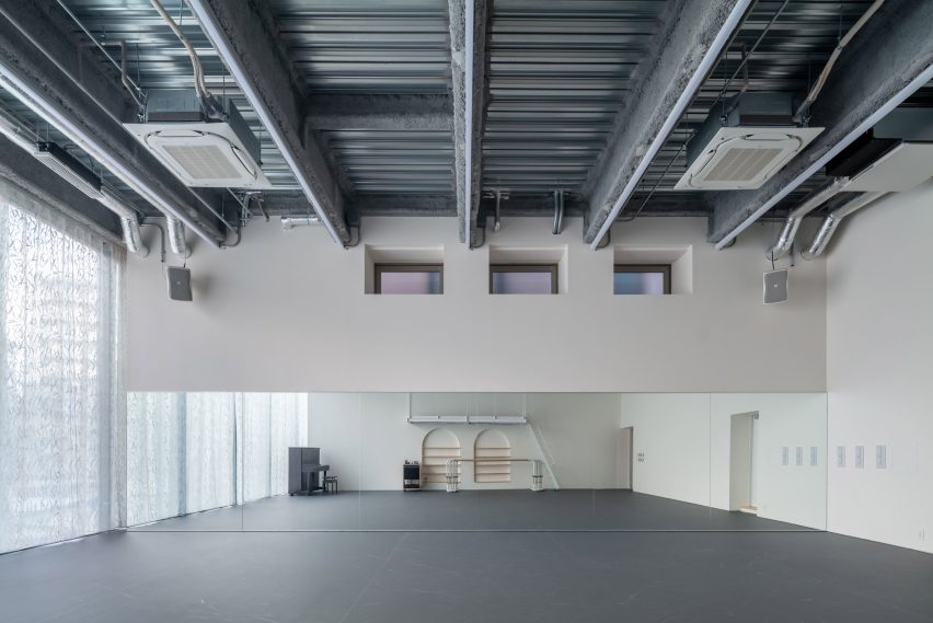 Empty ballet studio with mirrored wall, exposed steel structure and full-height curtain