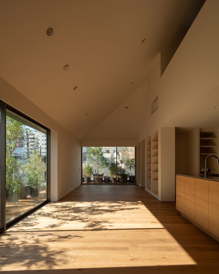 Sunlit living space with oak flooring leading to planted outdoor terraces through large sliding doors