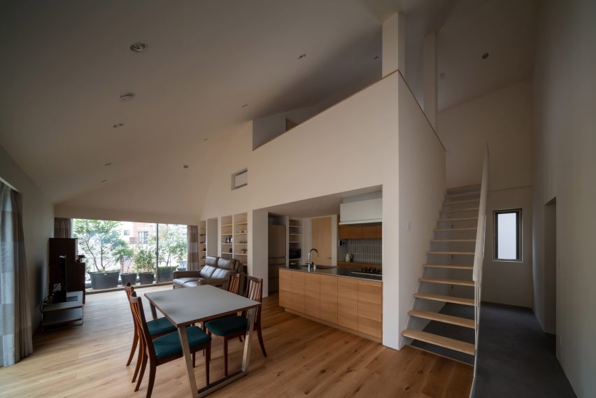 Open-plan living, dining and kitchen space with oak flooring beneath a sloping ceiling