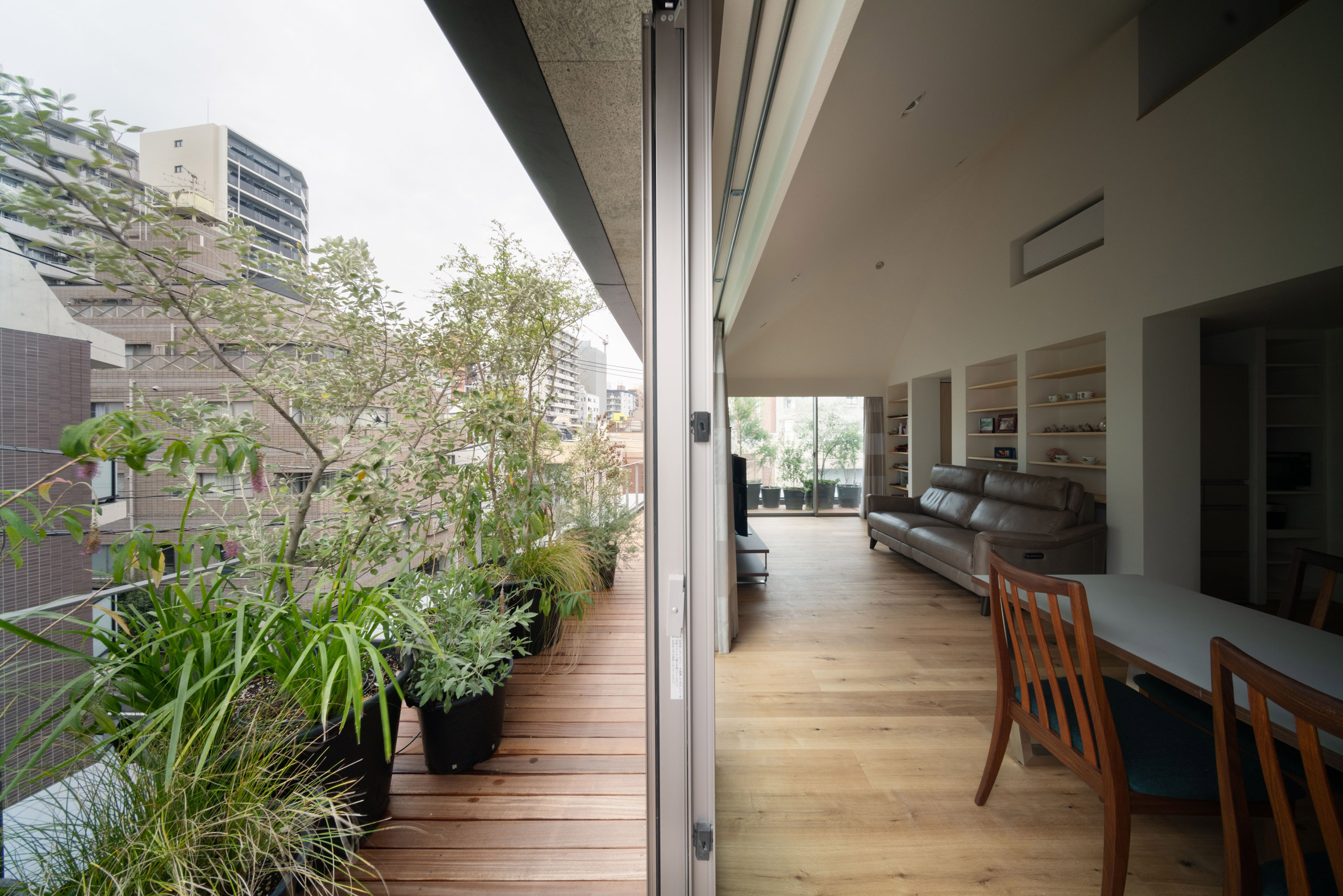 Las puertas corredizas se abren desde la sala de estar a una terraza circundante de madera plantada en el nivel superior.