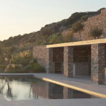 Rough drystone walls frame Within the Earth house in Greece