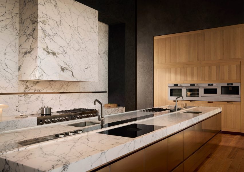 Image of a kitchen in golden wood with marble countertops and walls and Fisher & Paykel contemporary silver-coloured appliances integrated into the cabinetry and island