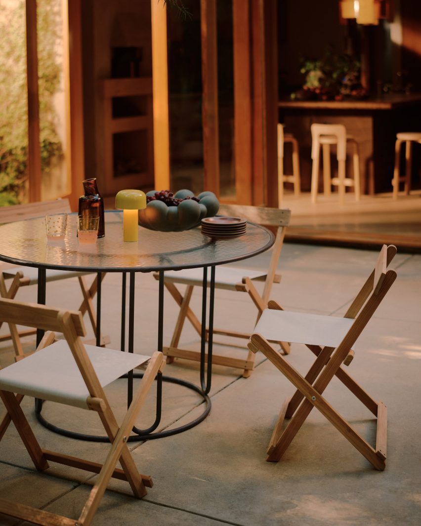 A glass-topped table and foldable wooden chairs create an outdoor dining setup