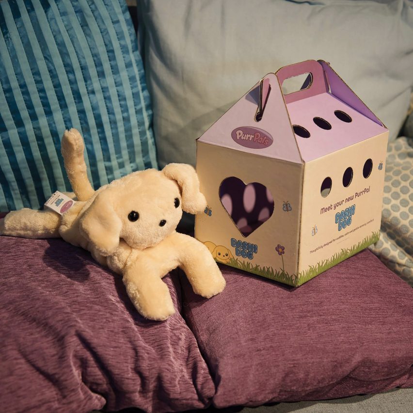 Toy dog sitting beside a cardboard carry crate