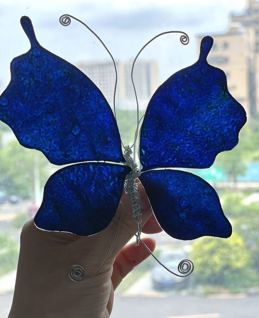 Photo of an ornamental butterfly made of wire with a translucent deep blue textile filling in its wings