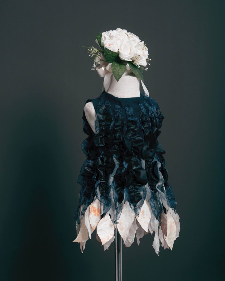 Photo of a dark blue dress with white ruffles on the bottom hem, sitting on a mannequin