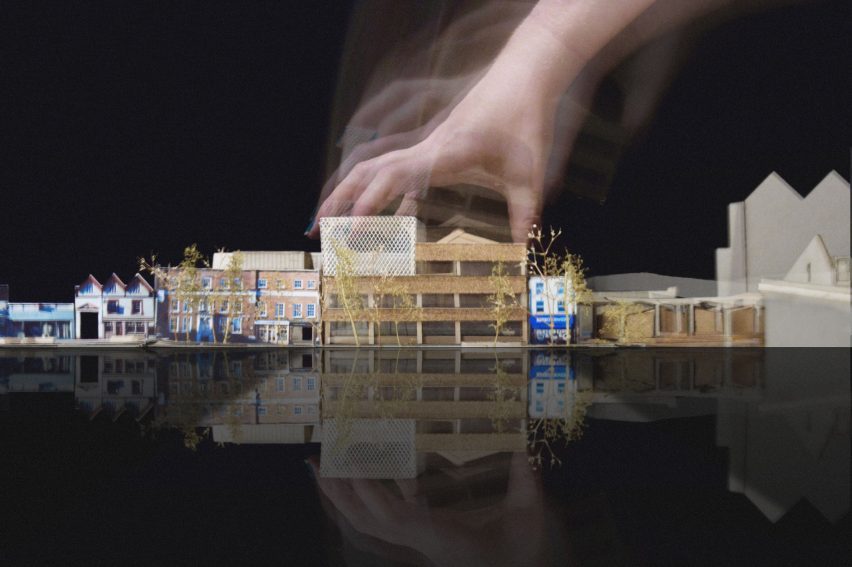 Hand grasping small architectural model of building