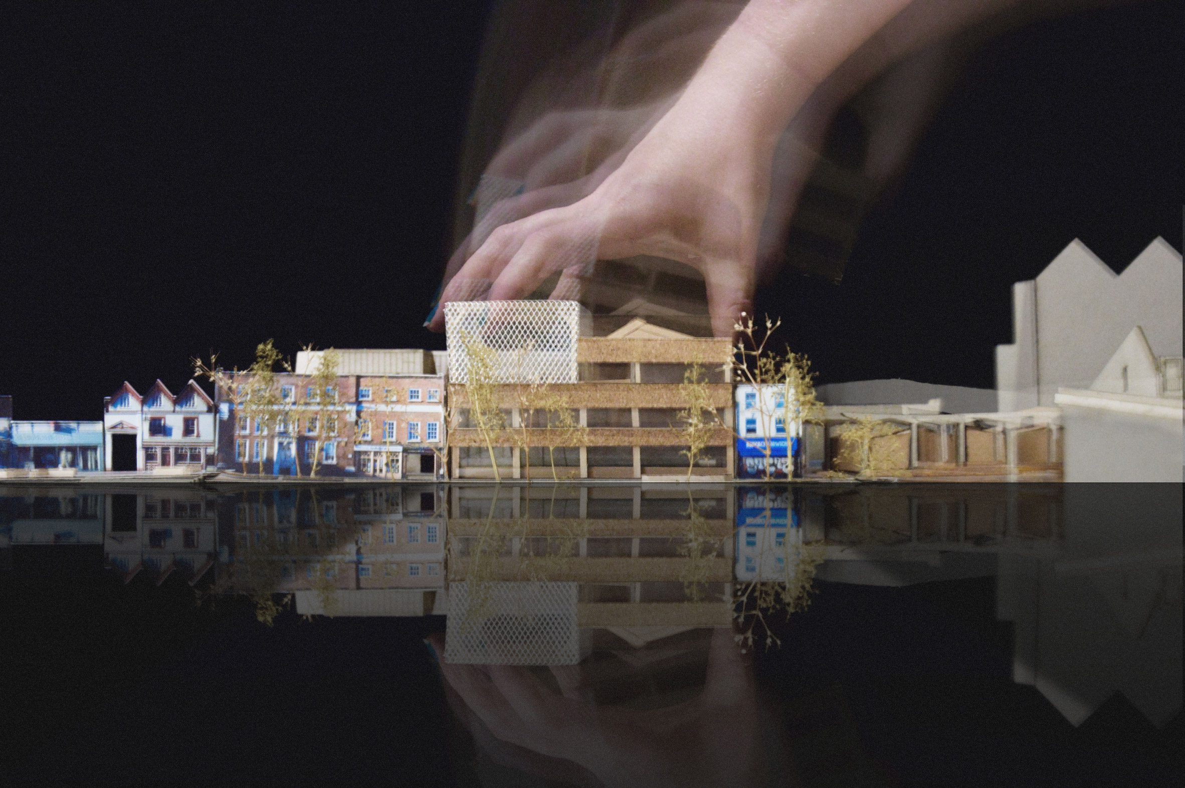 Hand grasping small architectural model of building