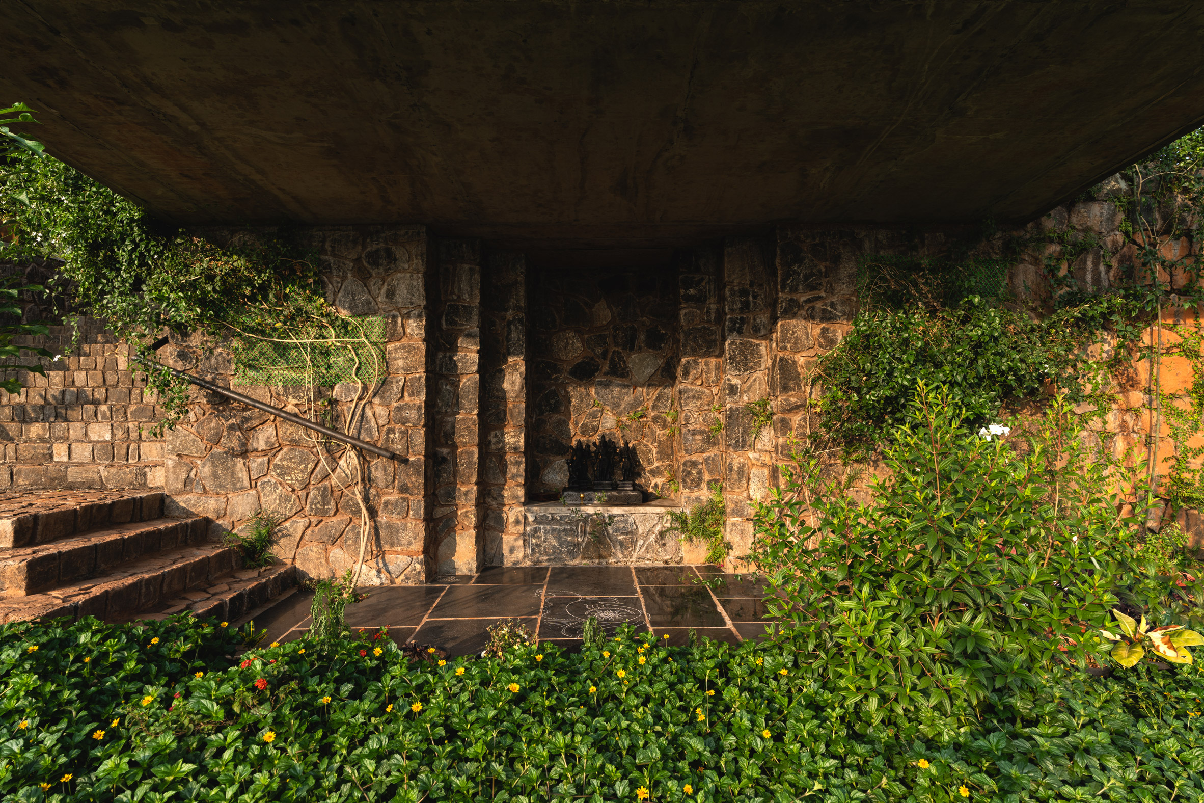 Open-air temple beneath Ushas farmhouse surrounded by planting