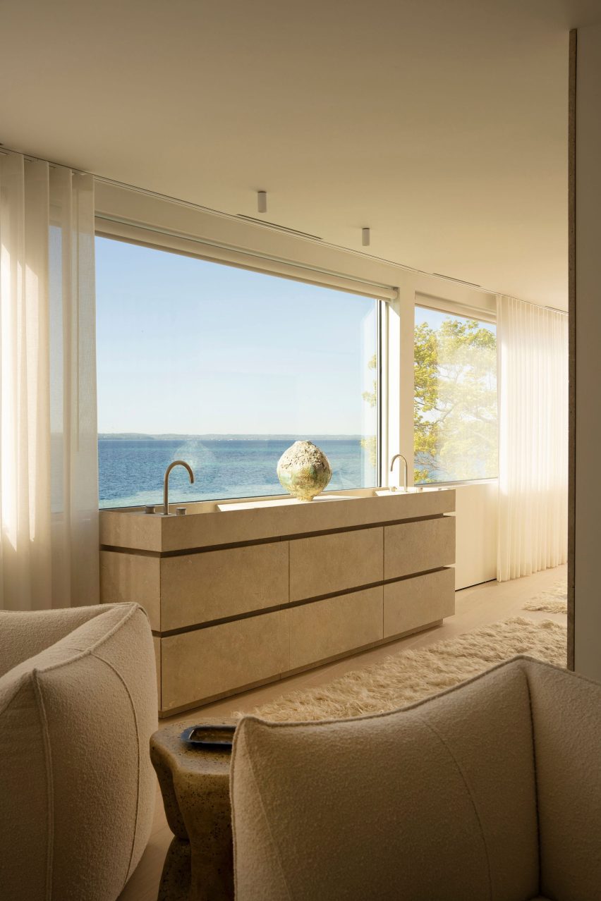A travertine vanity in a primary suite with a prime lake view