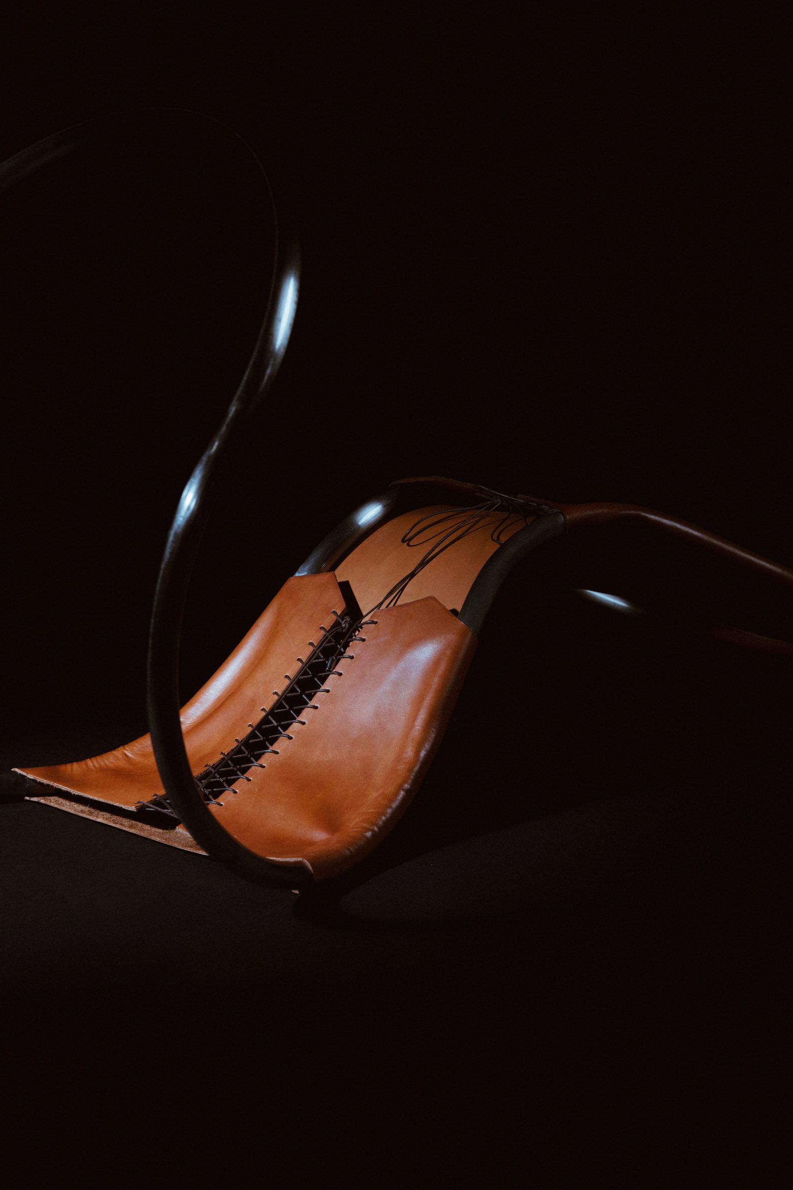 Photograph of a section of a chair that has been laid flat to showcase laced detailing, like a tanned leather corset.