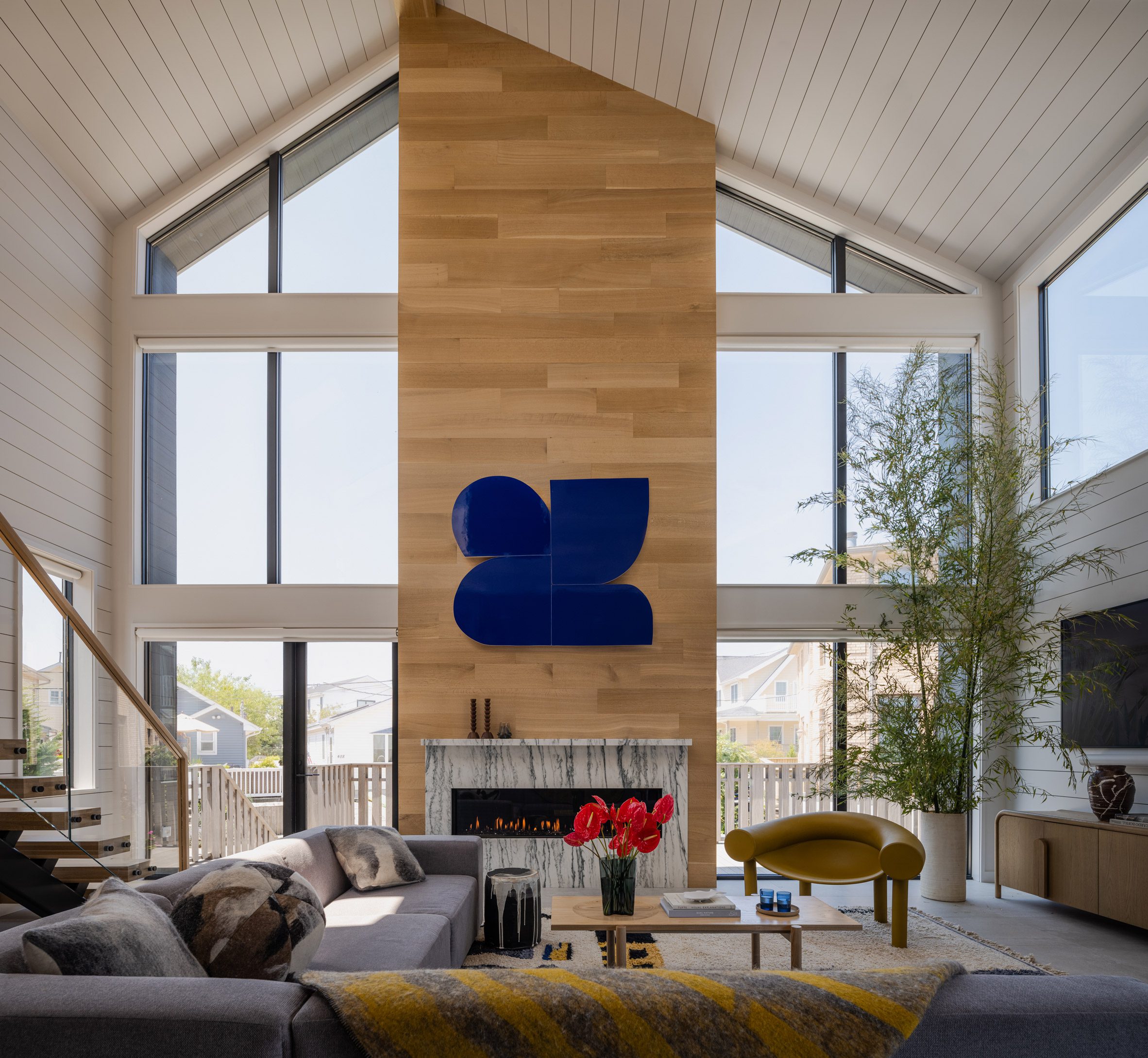 An oak-clad chimney stack sits between large windows in an airy family room