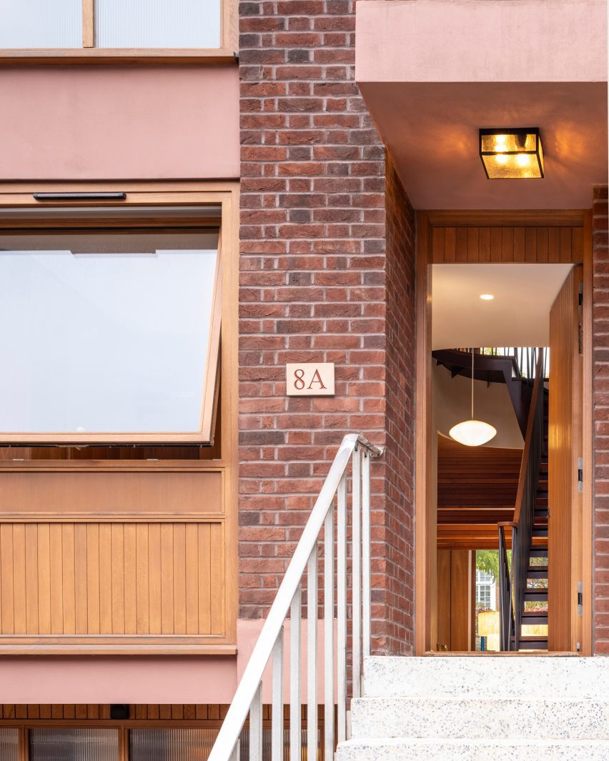 House entrance beneath pink-rendered concrete and timber-framed windows