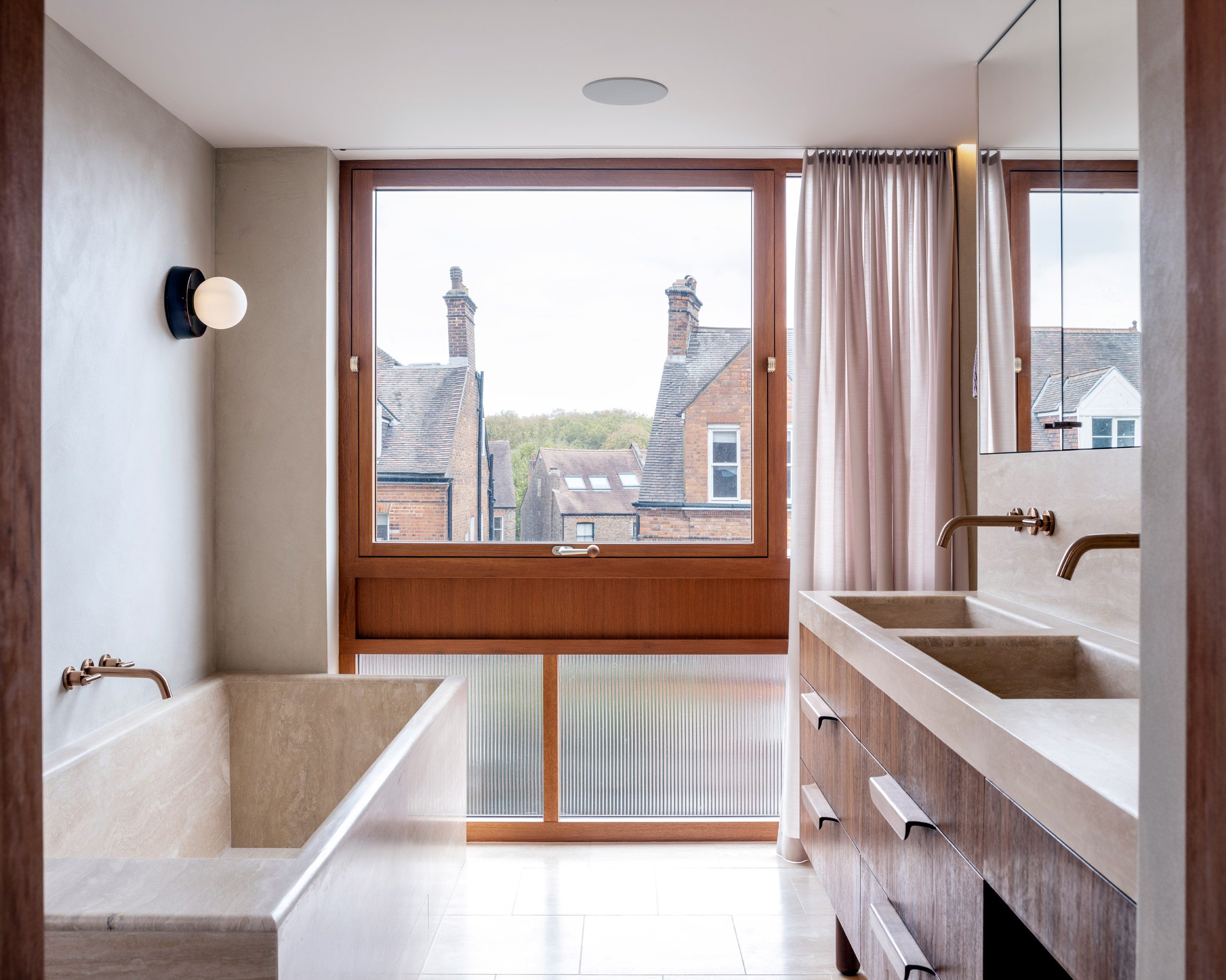 Bathroom with marble bathtub and vanity beside oak-framed windows