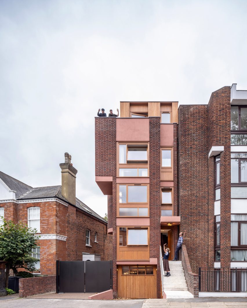 Front elevation of brick townhouse with timber-framed windows and roof-level timber extension