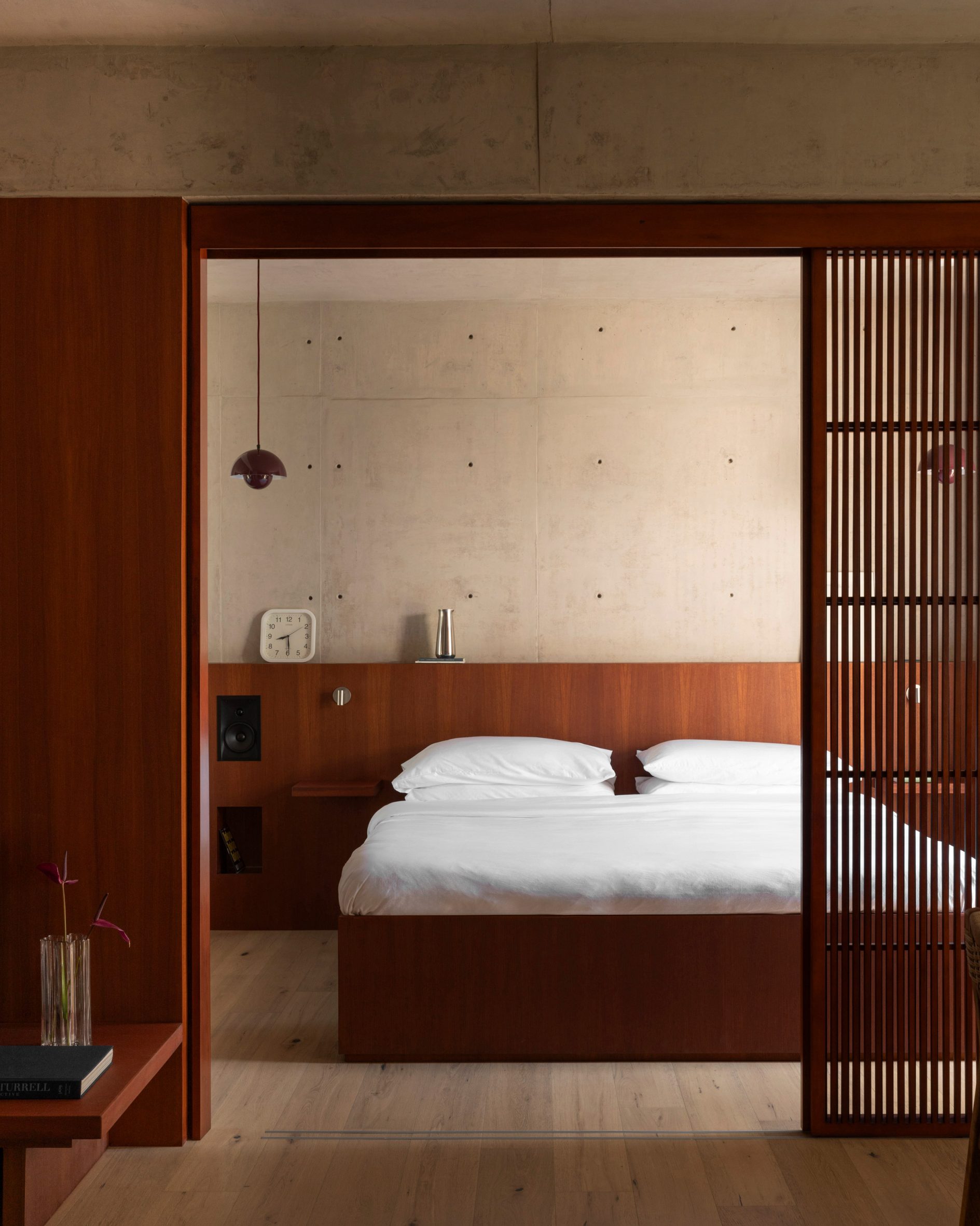 A bedroom is separated from a living area by a sliding slatted screen