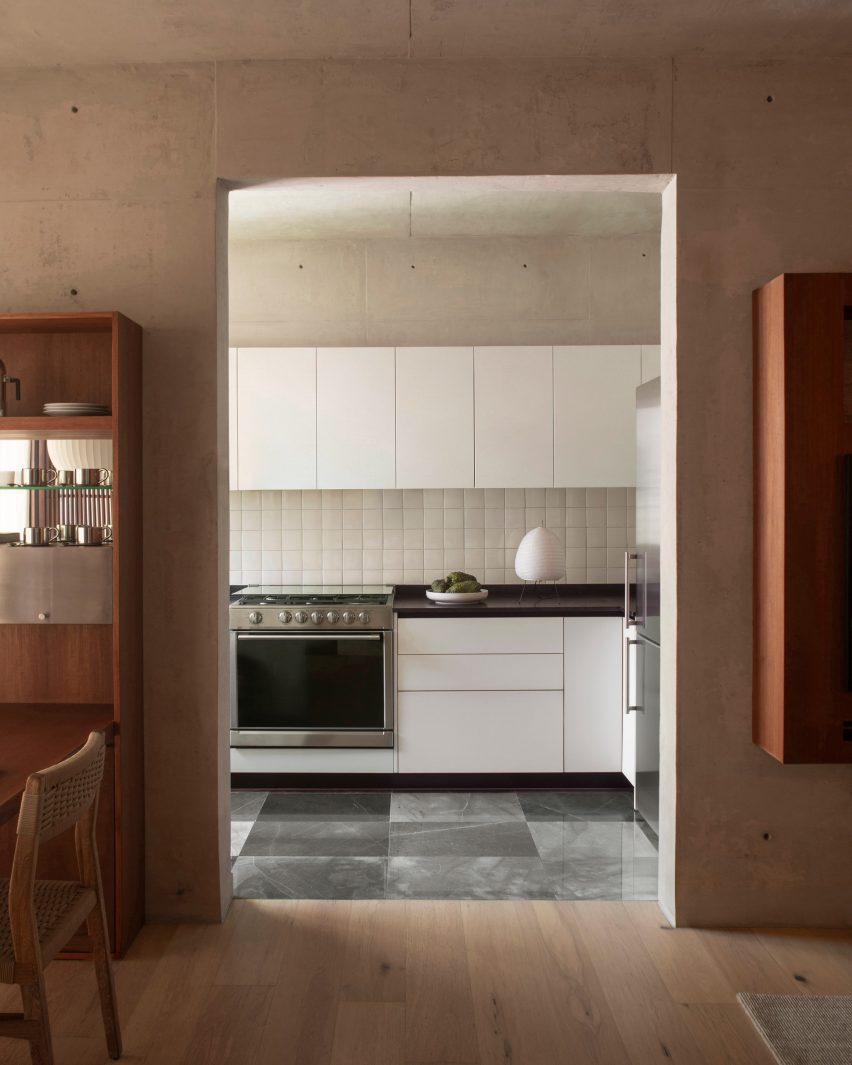 A black and white kitchen provides a contrast with rich wood furniture seen elsewhere