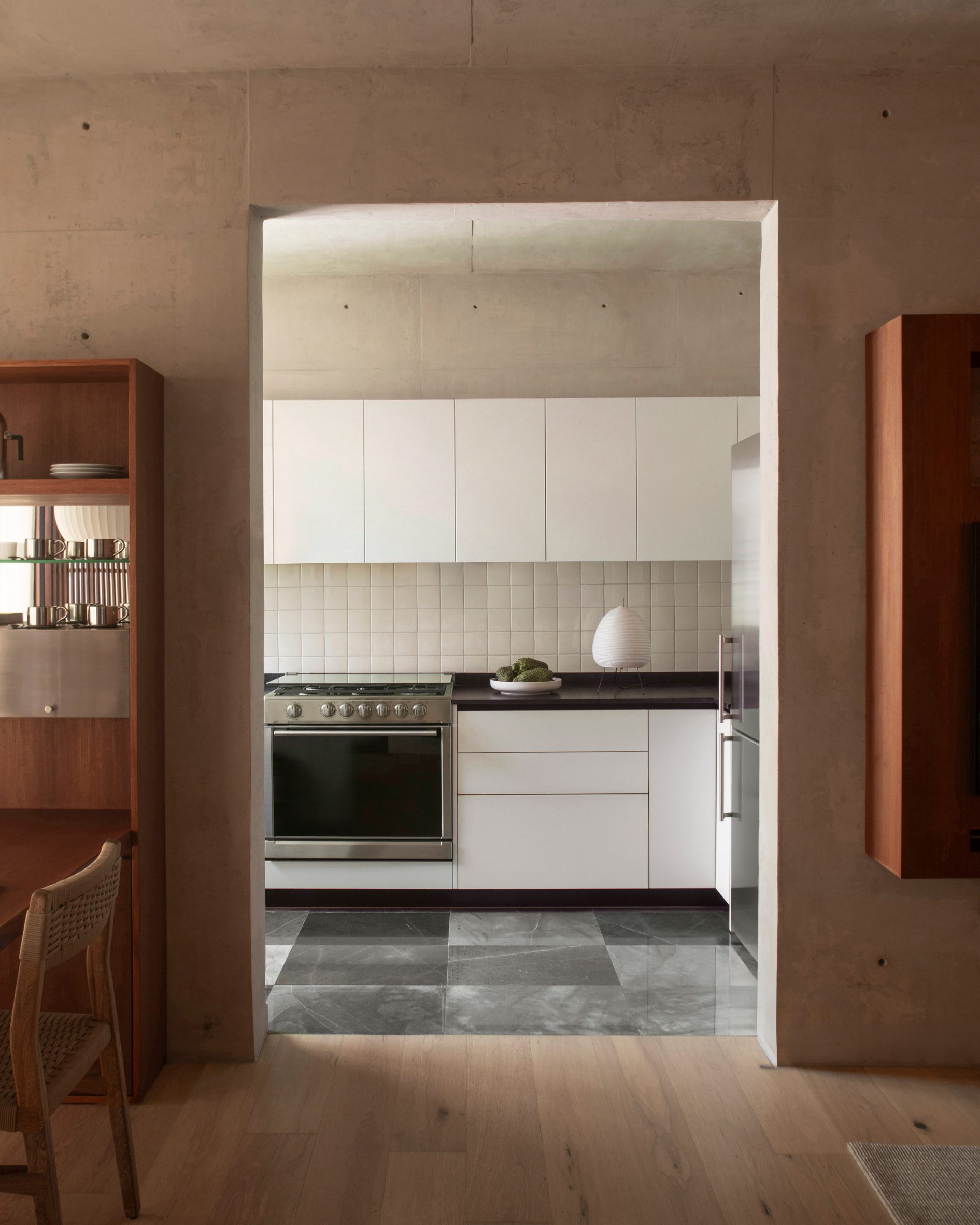 A black and white kitchen provides a contrast with rich wood furniture seen elsewhere
