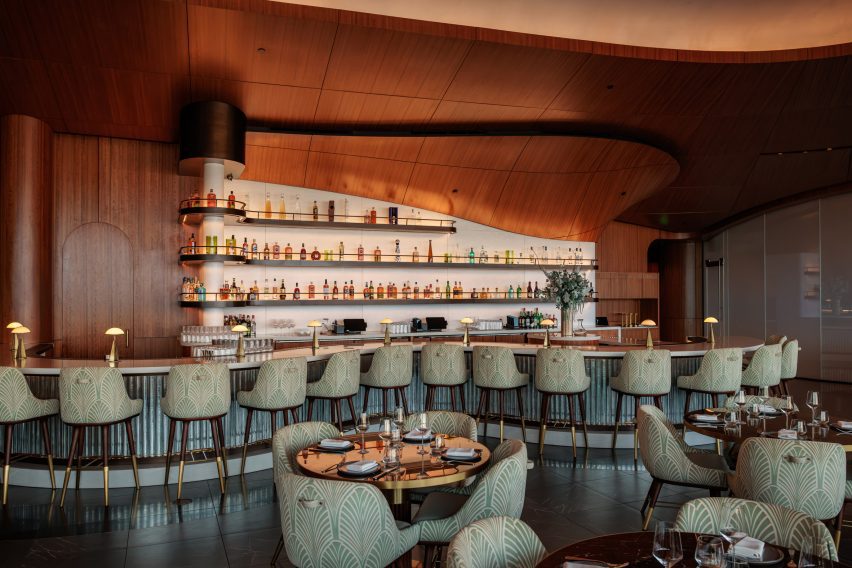 Shimmering tiles cover the front of a snaking bar, while the back bar is clad in illuminated Corian