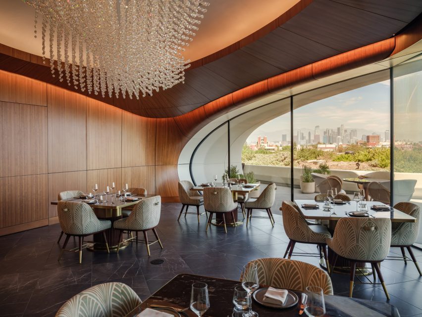 A large ovoid window opens onto a terrace with panoramic views