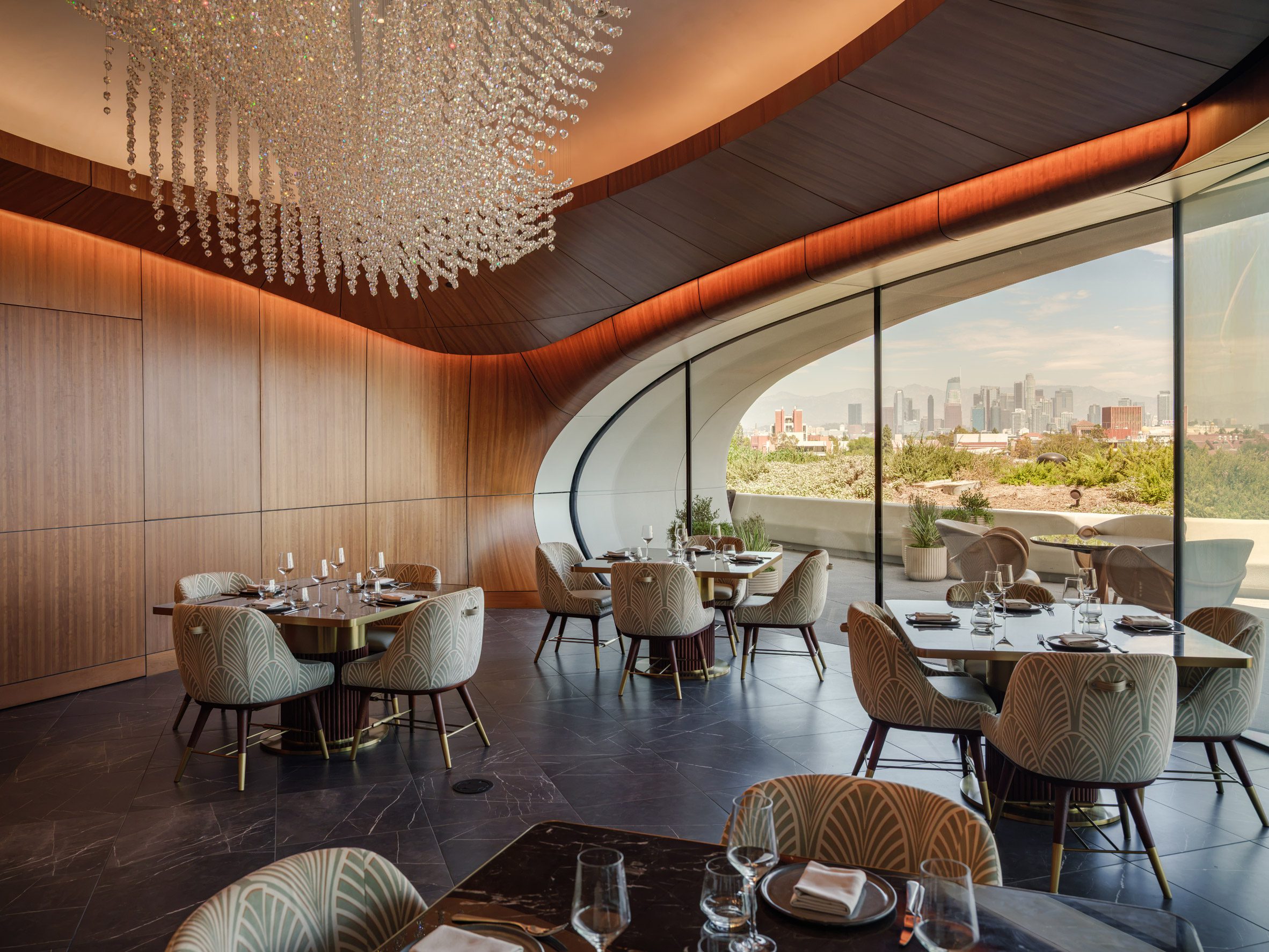 A large ovoid window opens onto a terrace with panoramic views