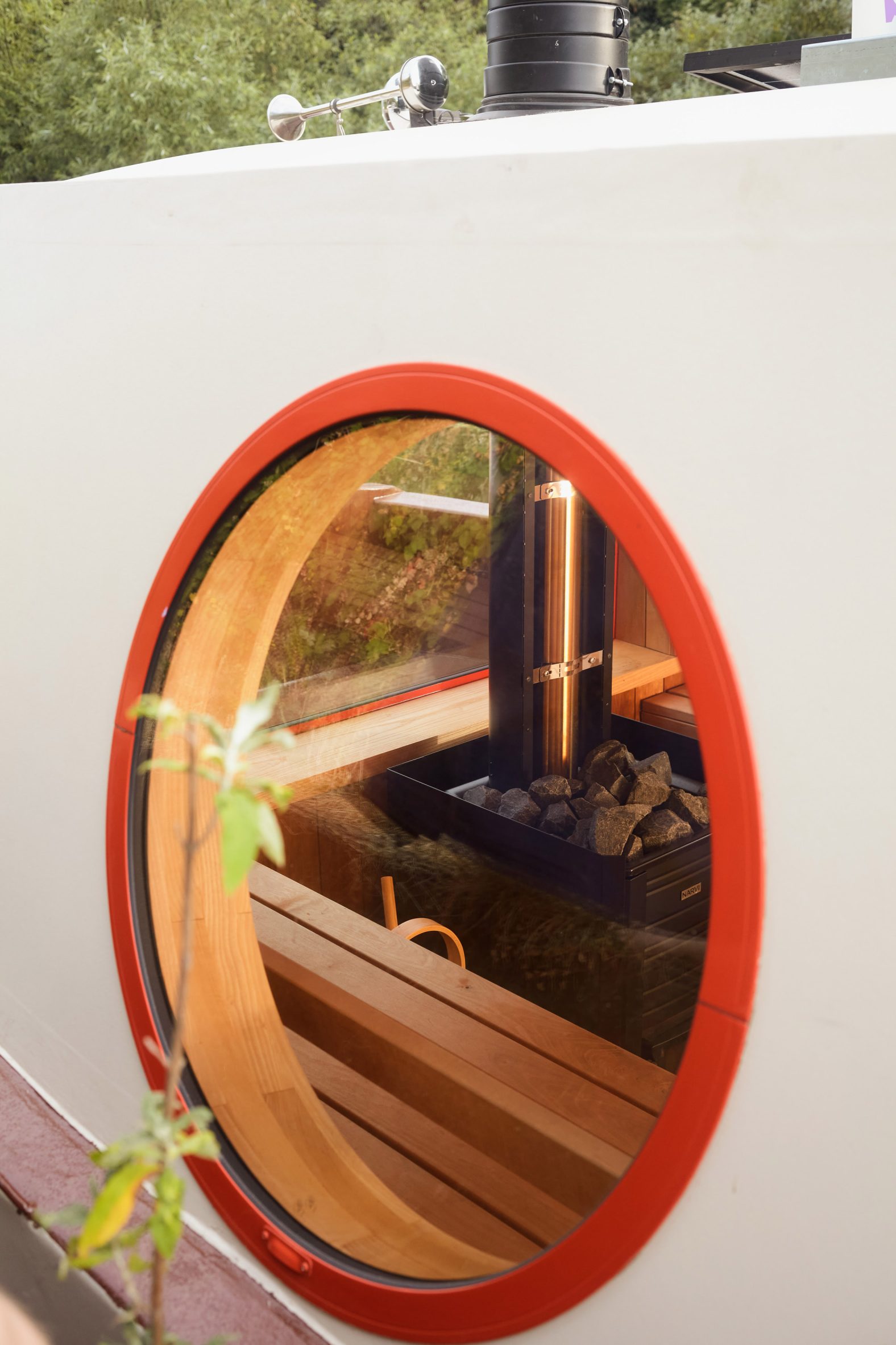 Large red-framed porthole on the cream exterior of Soak