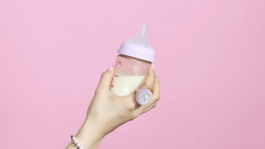Hand with a wearable video game ring holding a baby bottle
