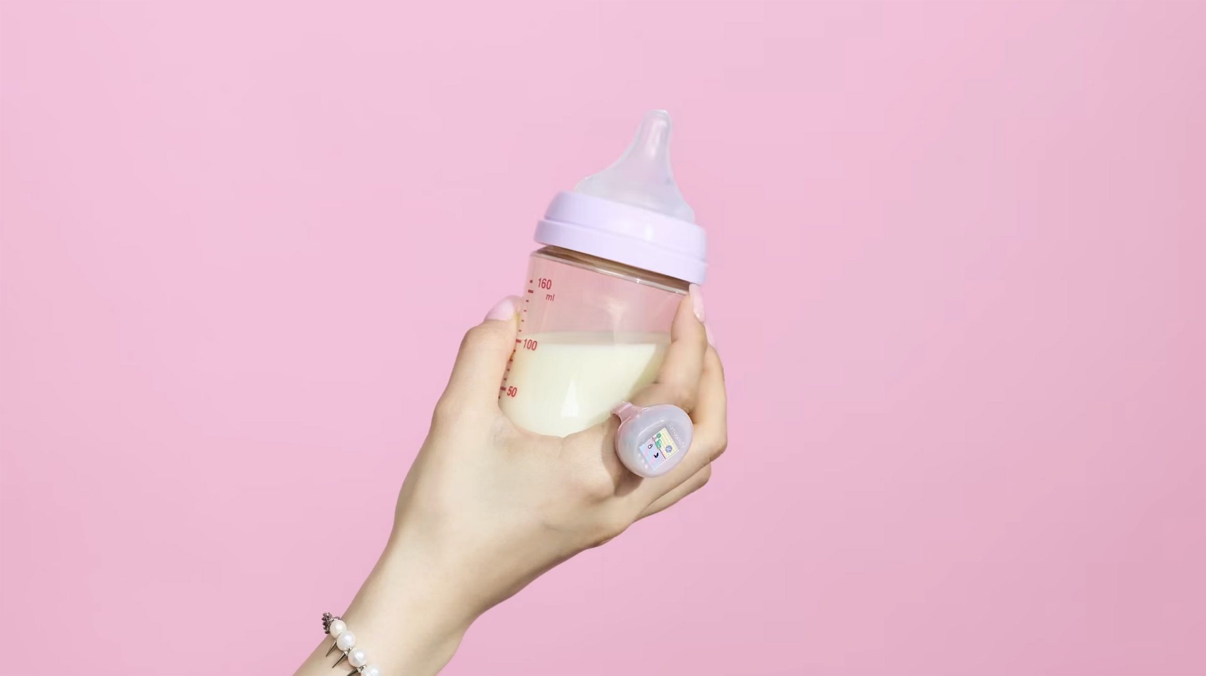 Hand with a wearable video game ring holding a baby bottle