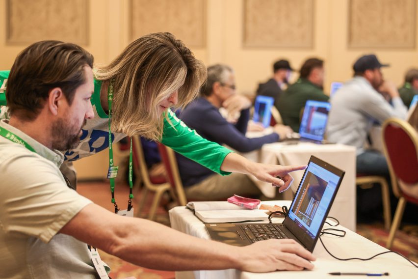 An attendee pointing to a laptop screen showing a SketchUp model