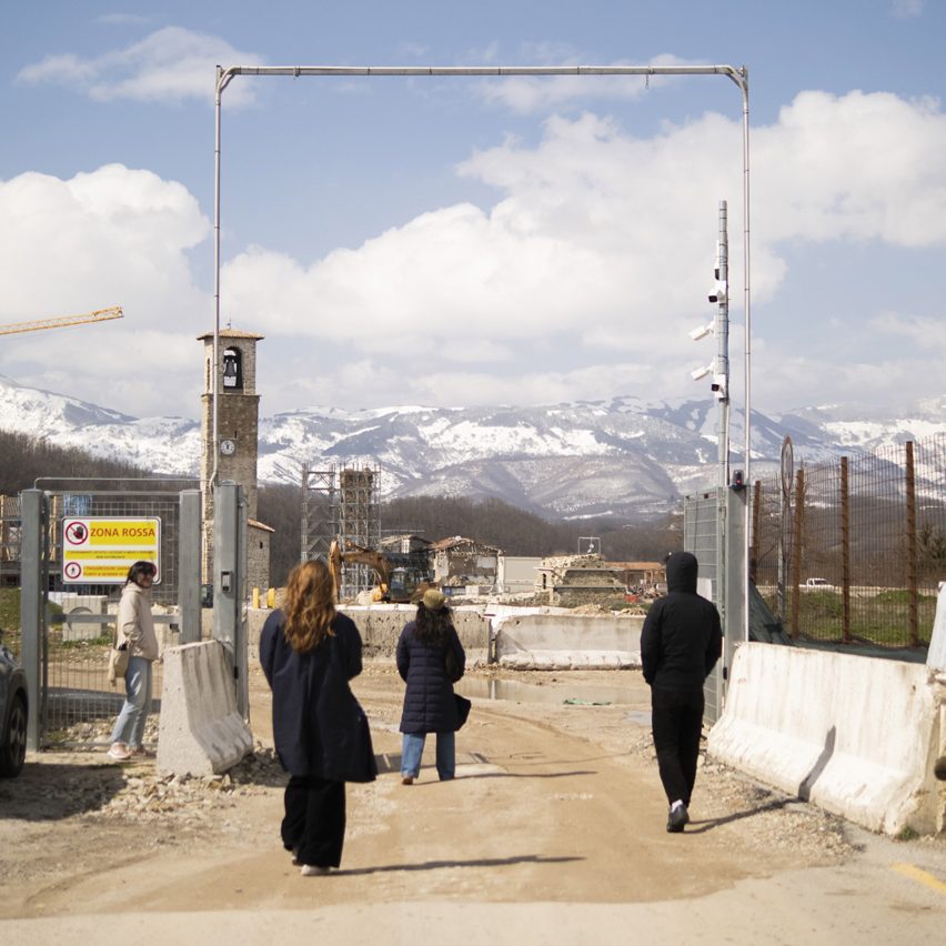 People walking into a construction site at the foot of some snow-capped mountains