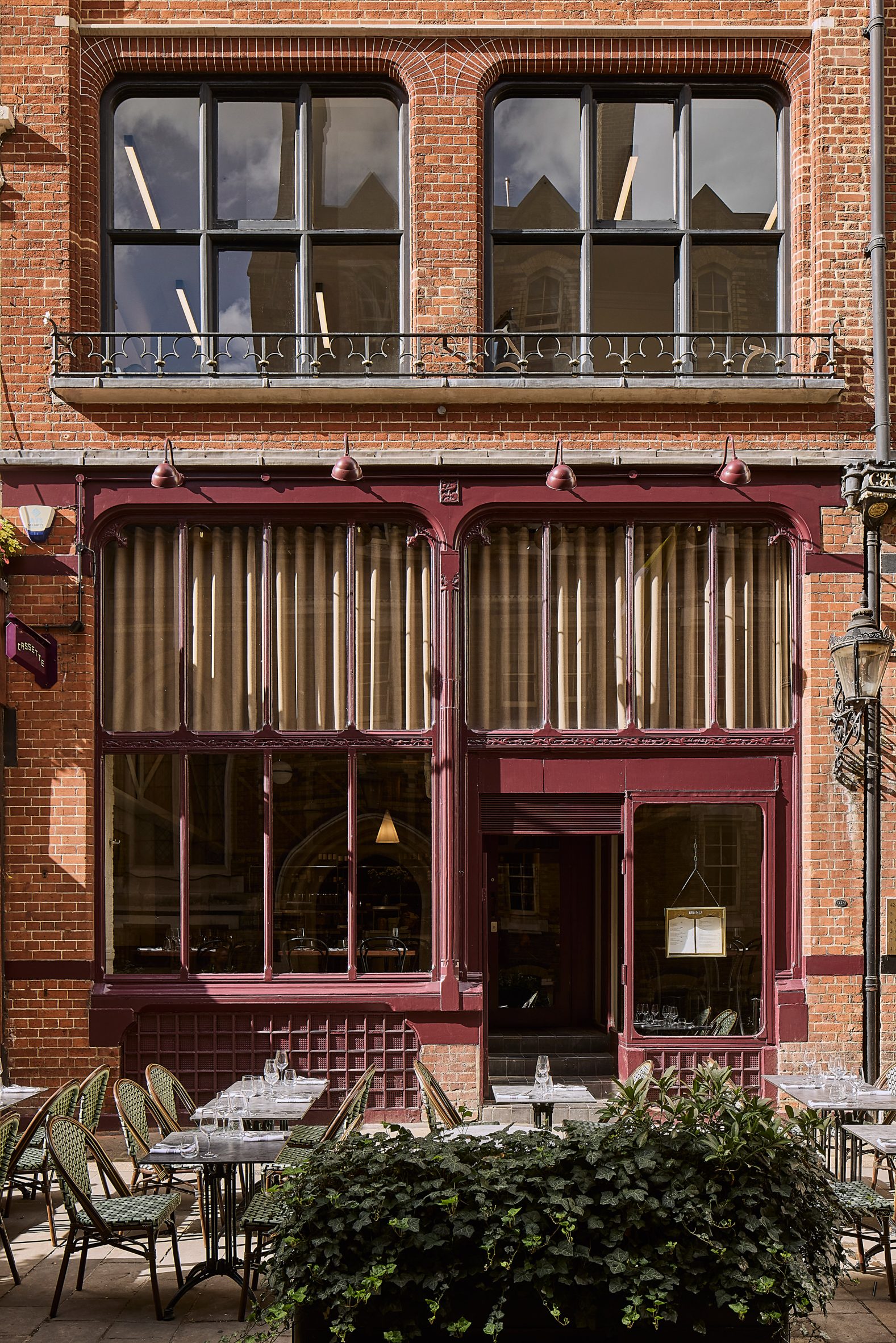 Photograph of the exterior of the restaurant, showing deep aubergine painted window panes and the terrace area.