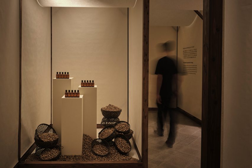 Fragrance bottles and bowls of raw ingredients displayed inside a washi paper installation