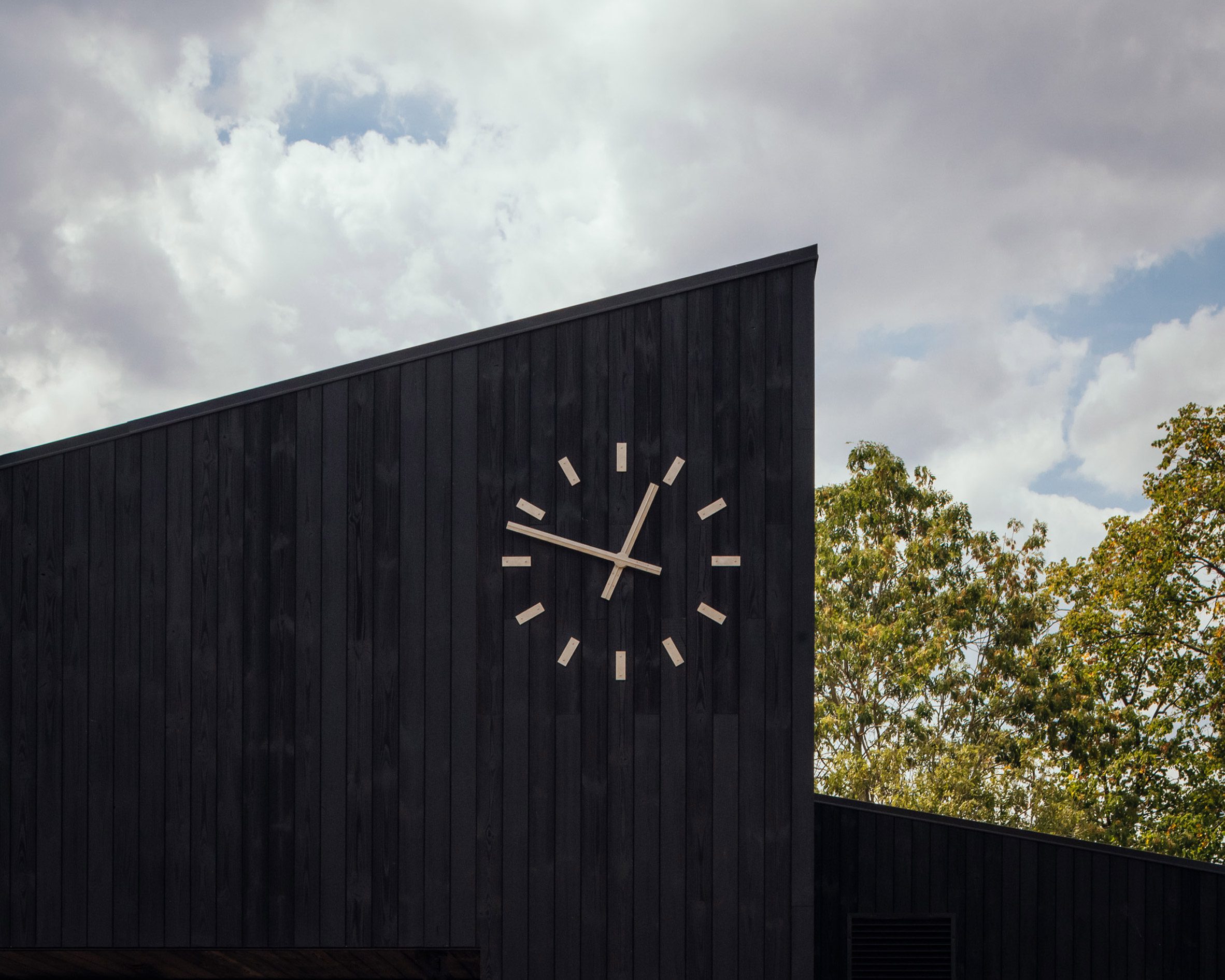 White clock on black cricket pavilion
